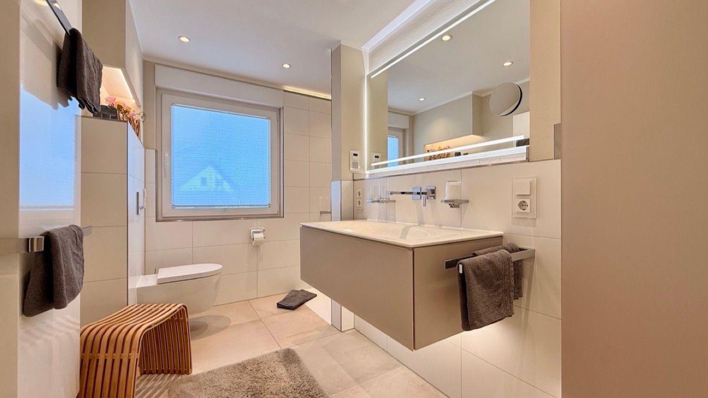 Moderne Badewanne mit Spiegel, Toilette und Fenster mit Blick.