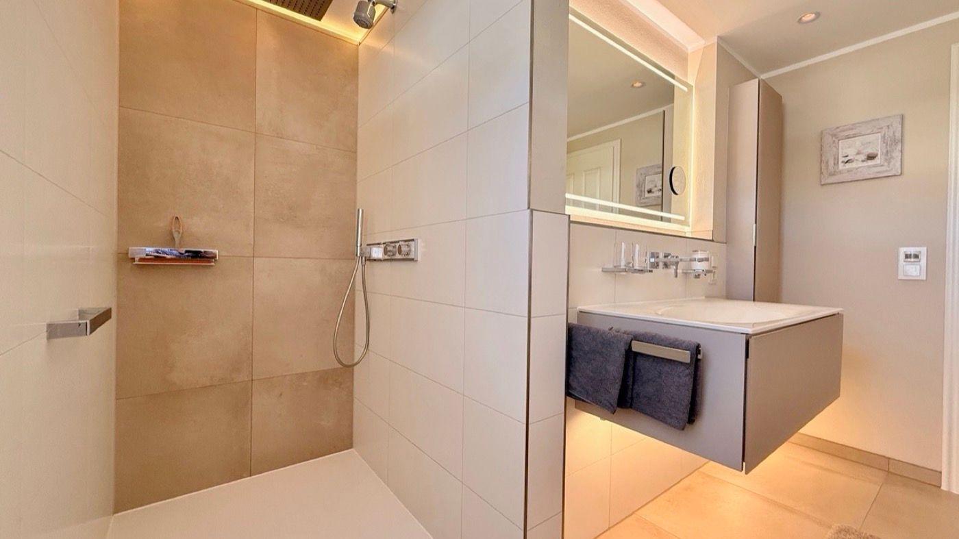 Moderne Dusche mit Handbrause und integriertem Waschbecken mit Spiegel.