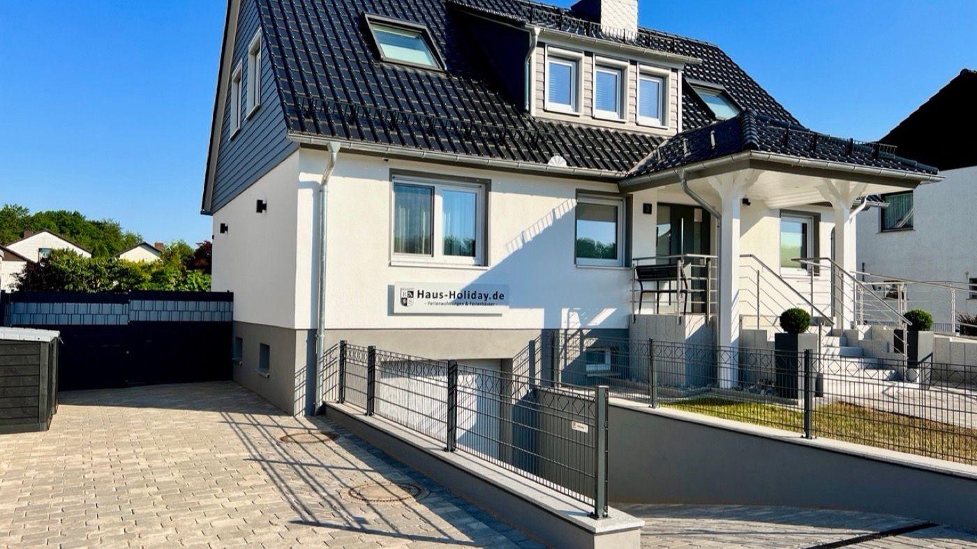 Modernes Haus mit Terrasse und Garten. Eingangsbereich mit Stufen und Geländer.