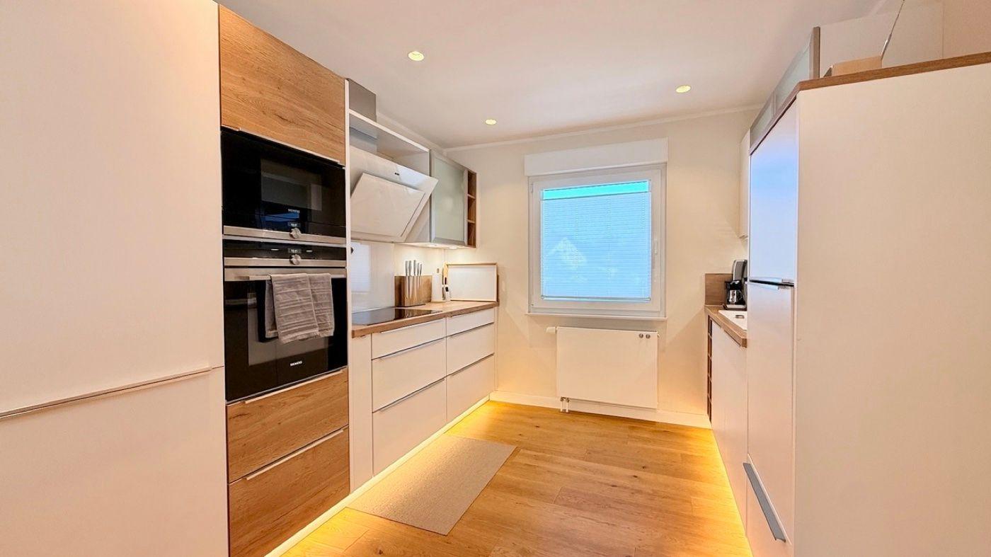 Moderne Küche mit Holzoptik, integriertem Ofen und Küchenzeile.