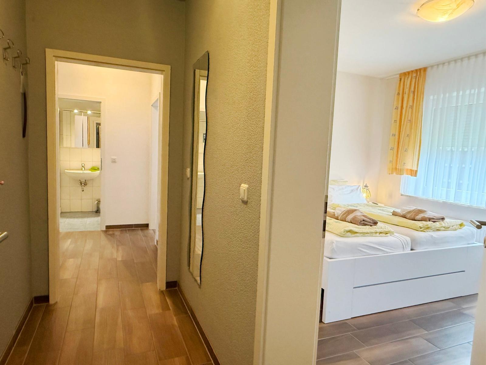 Schlafzimmer mit Doppelbett und Bad im Hintergrund.