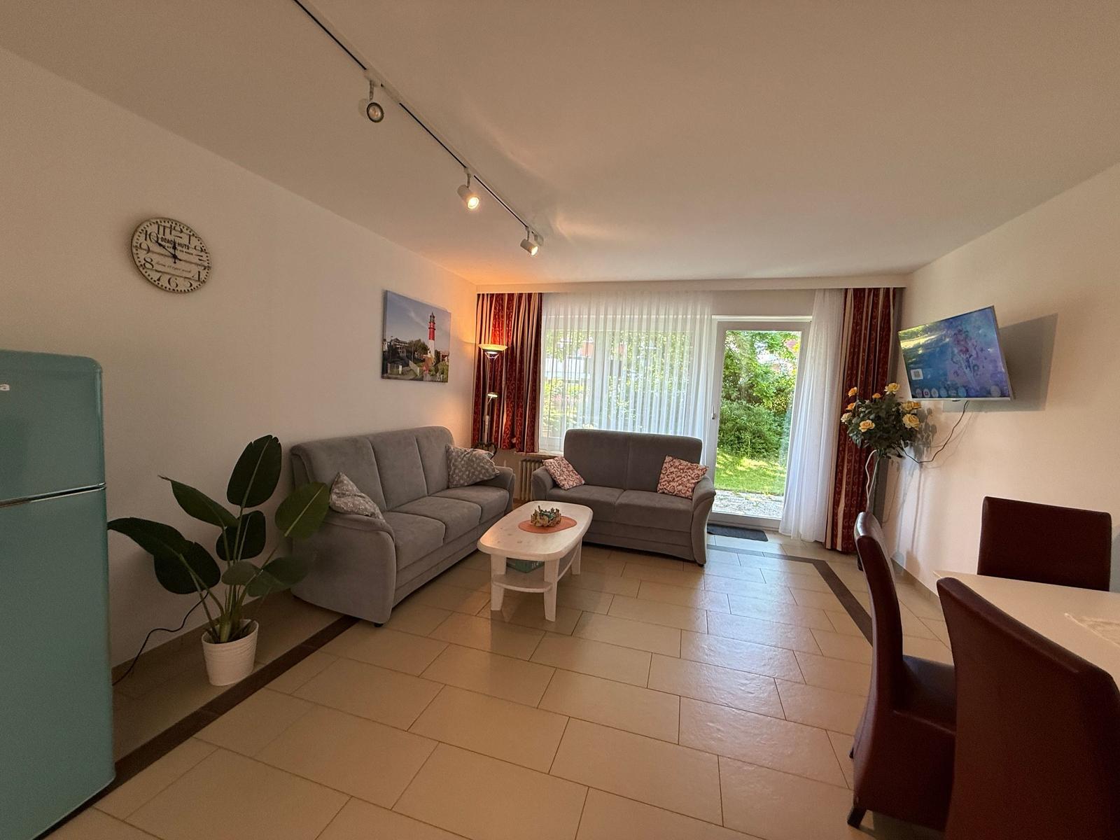 Wohnzimmer mit Sofa, Fernseher und Blick auf Garten.