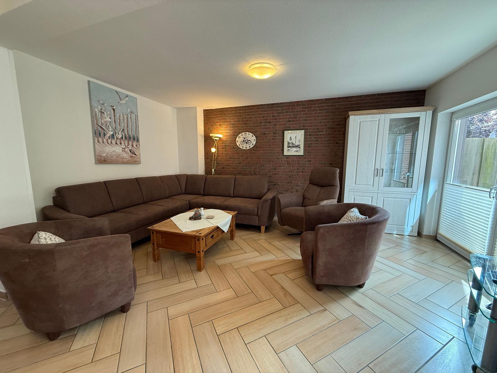 Wohnzimmer mit braunem Sofa, Holztisch und Ziegelwand