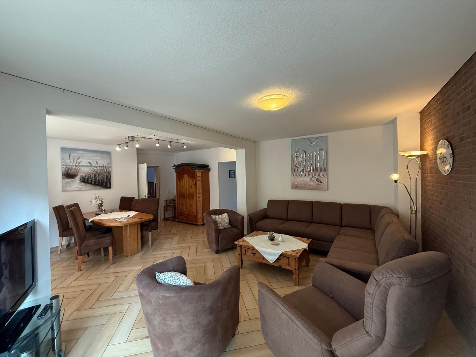 Wohn- und Essbereich mit Sofa, Stühlen und Holzboden.