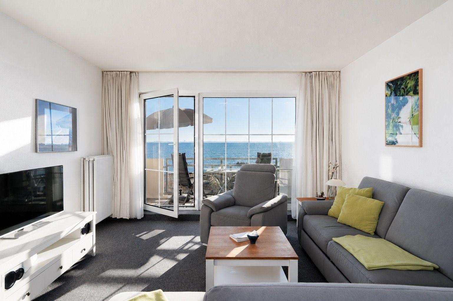Wohnzimmer mit Blick aufs Meer, Sofa, Sessel und TV.