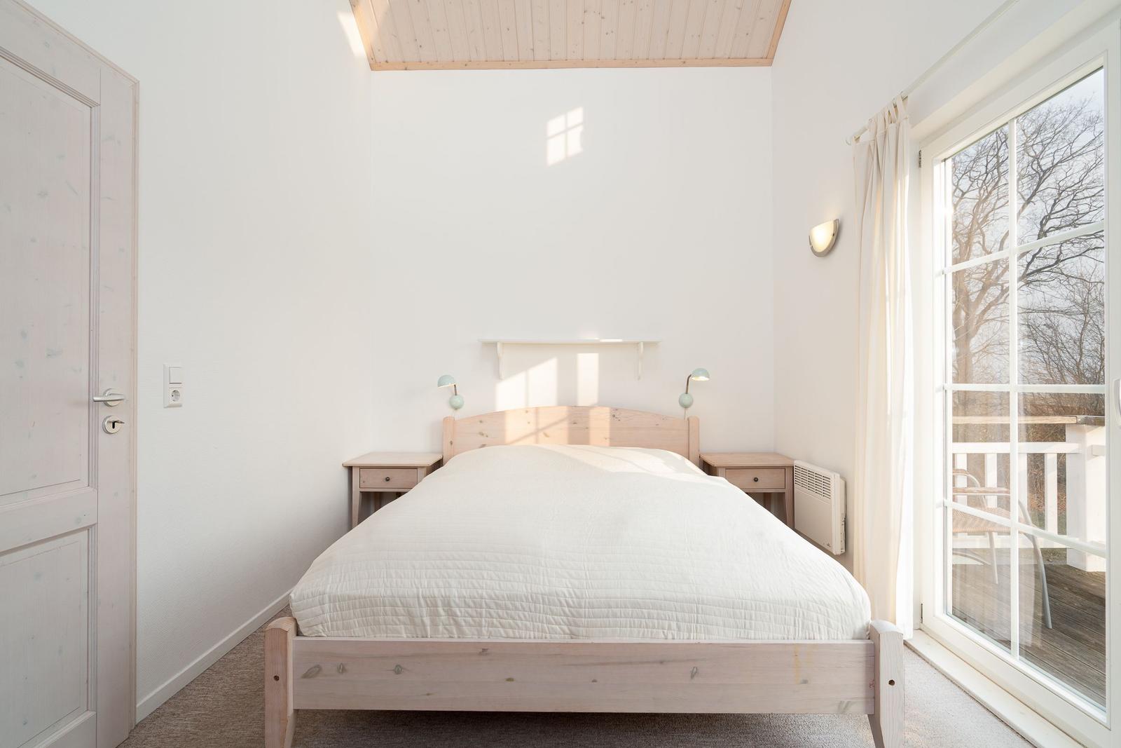 Bedroom with wooden bed, nightstands, and window to terrace.