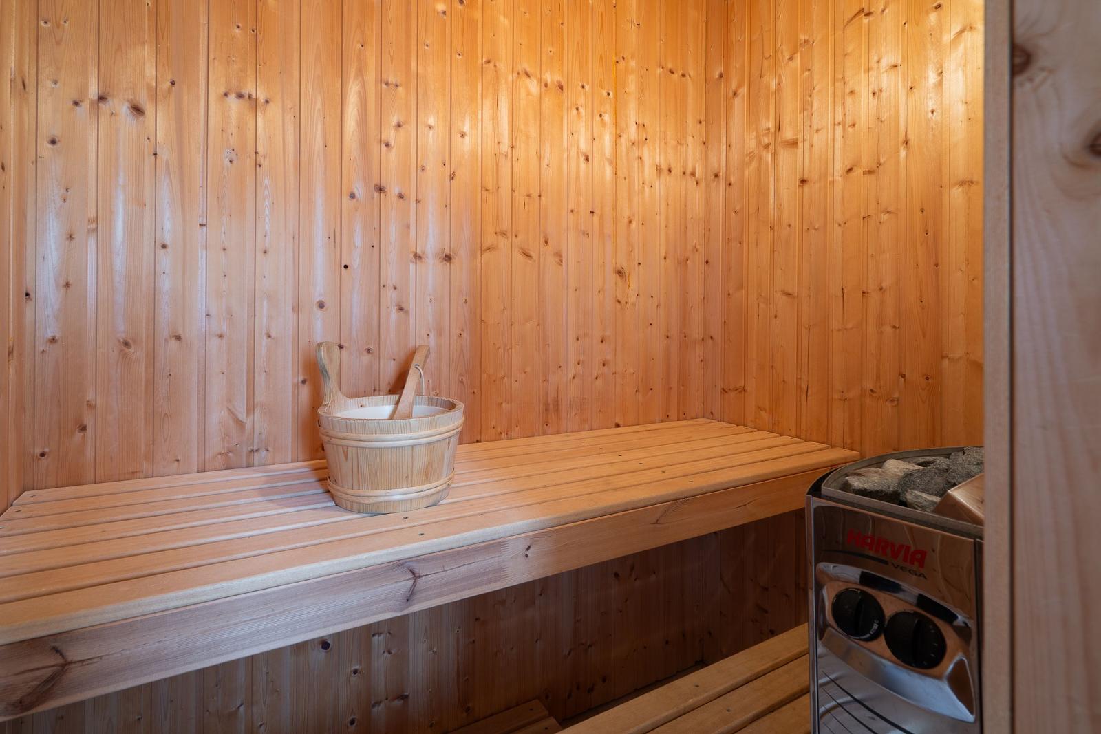 Sauna with wooden walls, bench, and wooden wash bucket.
