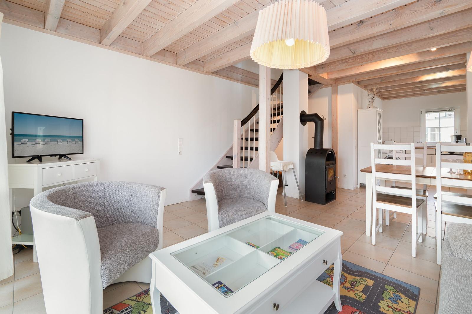 Living and dining area with wooden beams, TV, seating, and dining table.