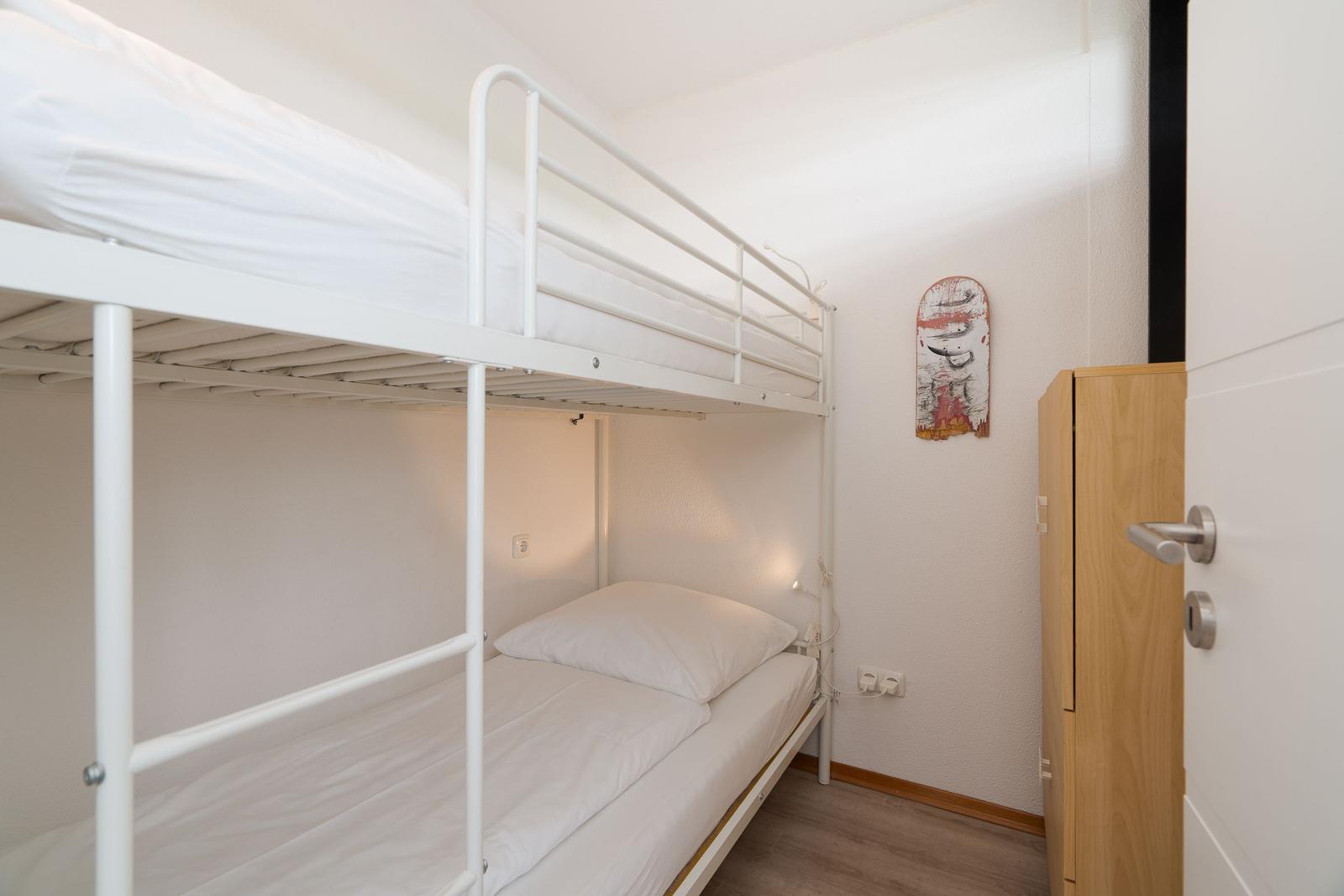 Zimmer mit Doppelstockbett, Schrank und Wanddekoration.