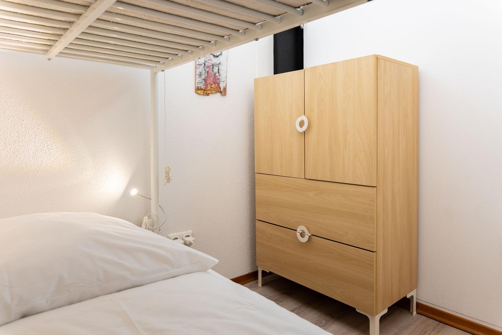 Schlafzimmer mit Bett, Kleiderschrank und Deckenbett.
