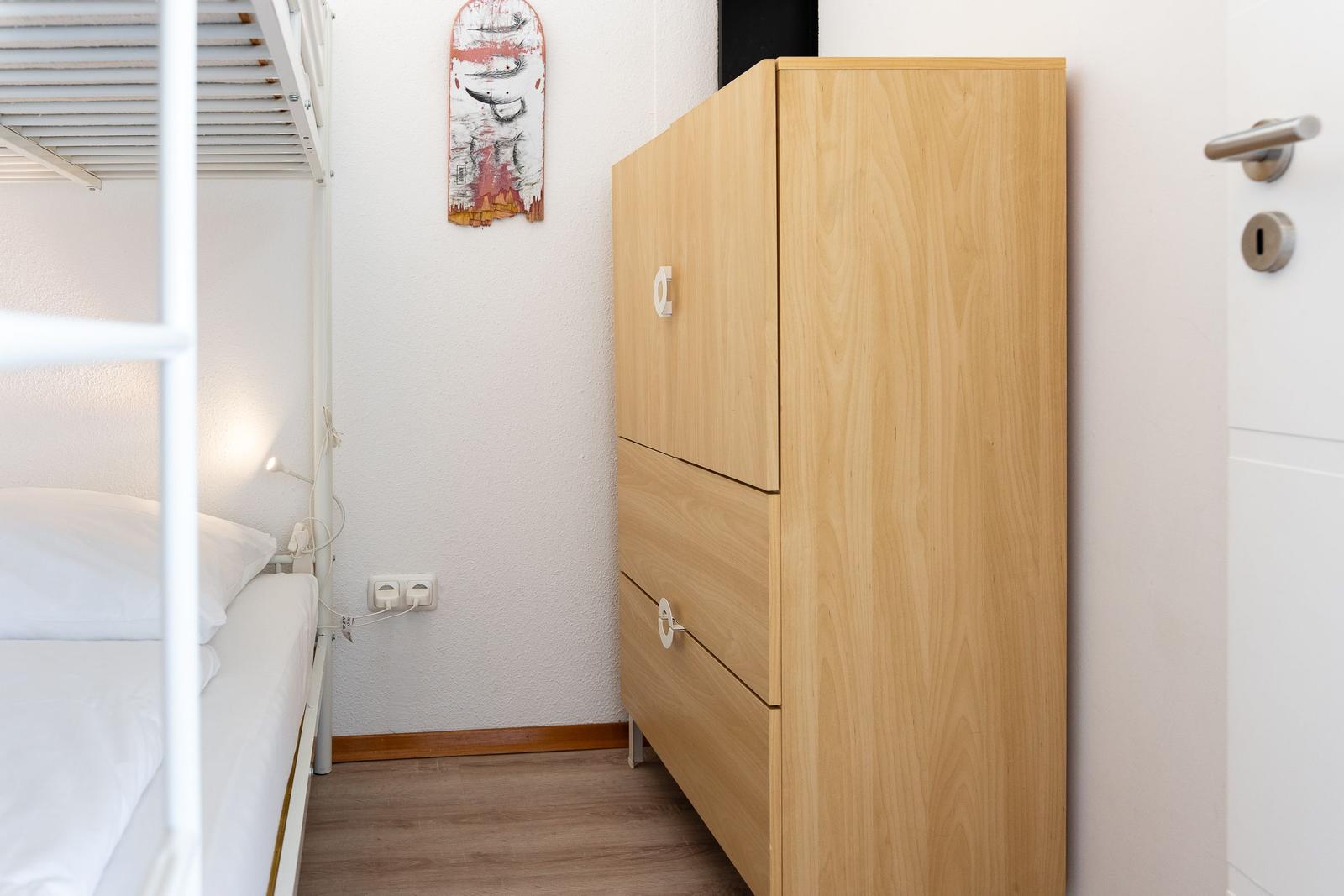 Schlafzimmer mit Doppelstockbett, Holzschrank und Wandbild.