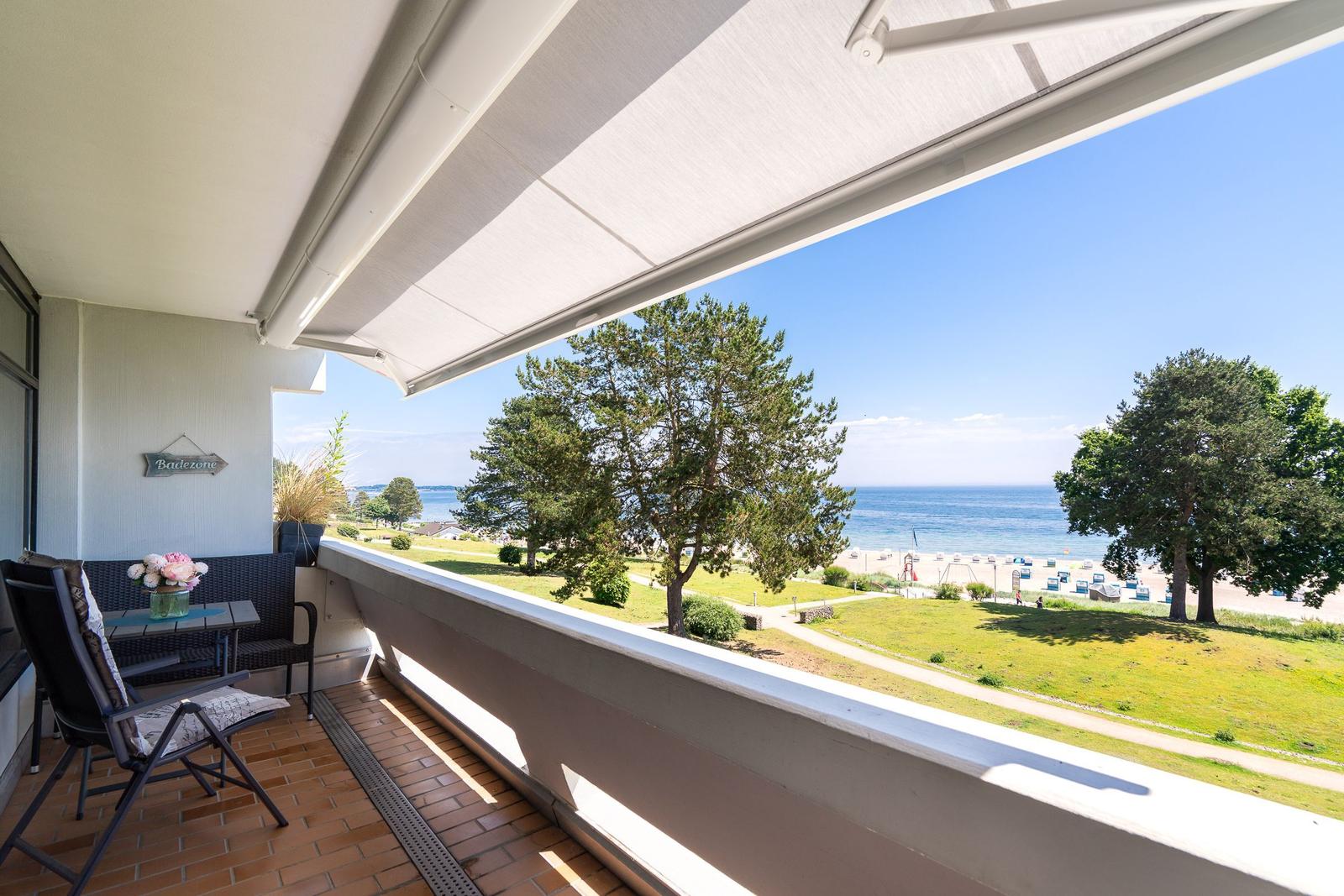 Terrasse mit Blick auf Strand und Meer. Sitzgelegenheit und Markise.