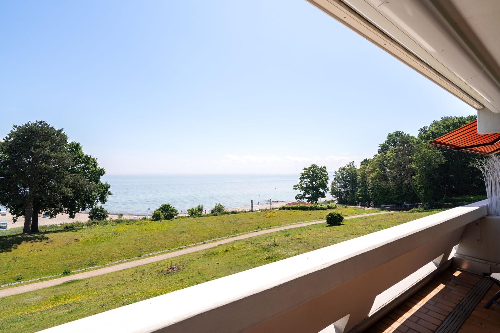 Balkon mit Blick auf Strand und Meer unter blauem Himmel.