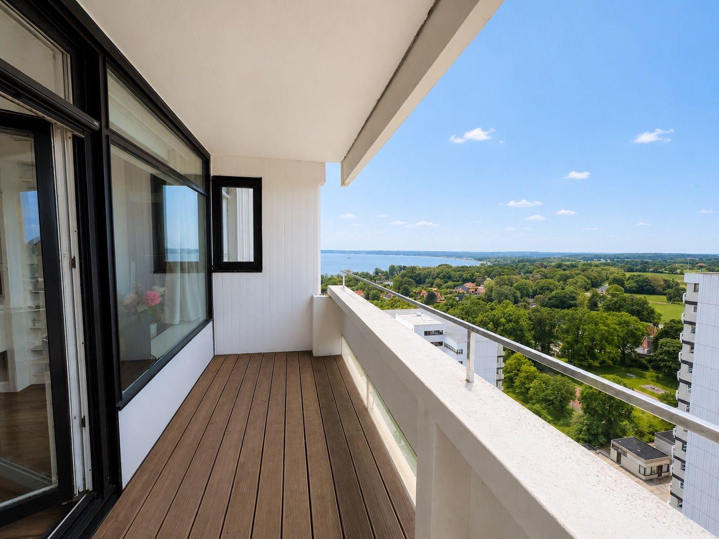 Balcony with wooden floor and view of water and green areas