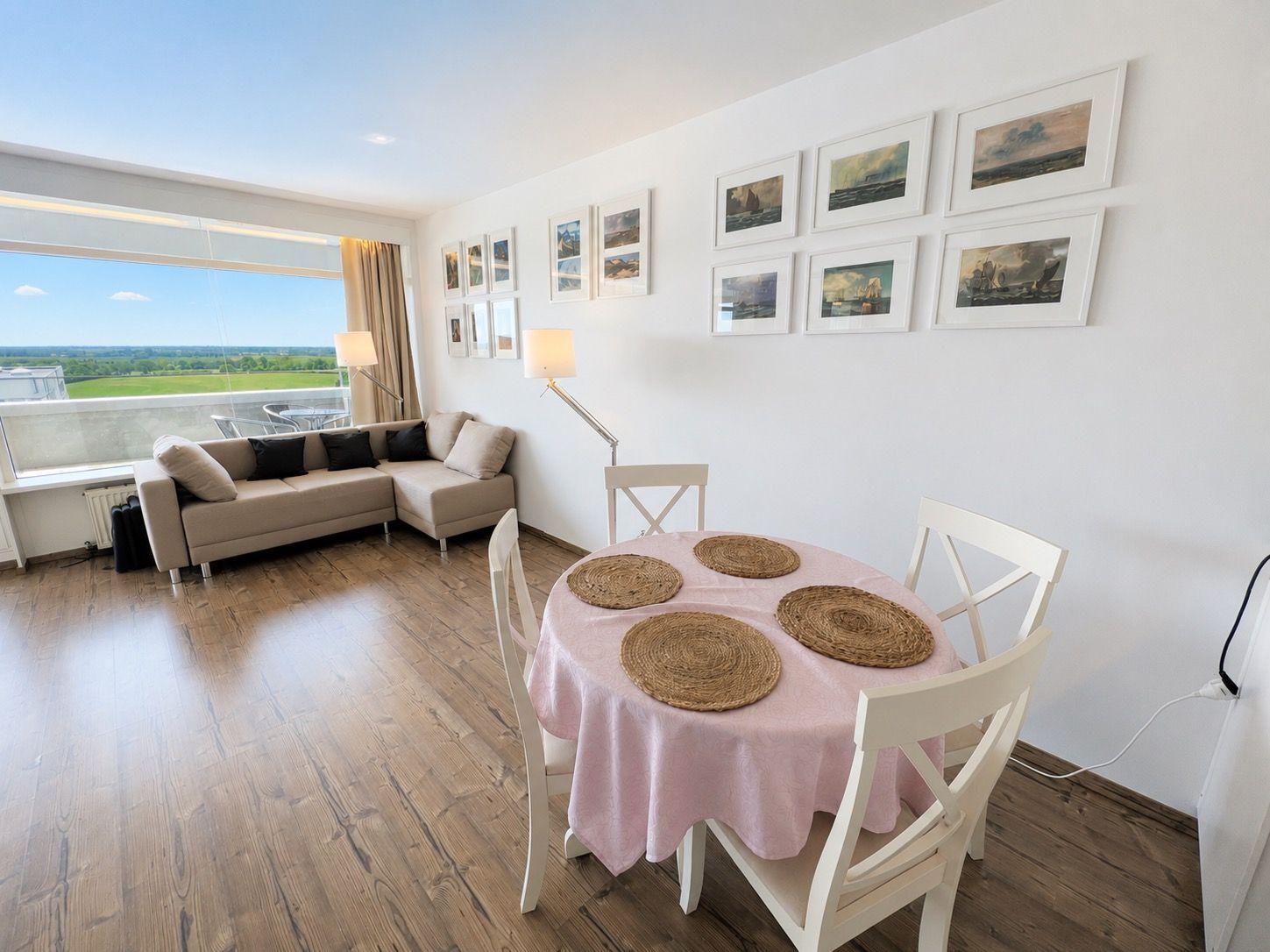 Living and dining area with table, chairs, and view of the landscape.