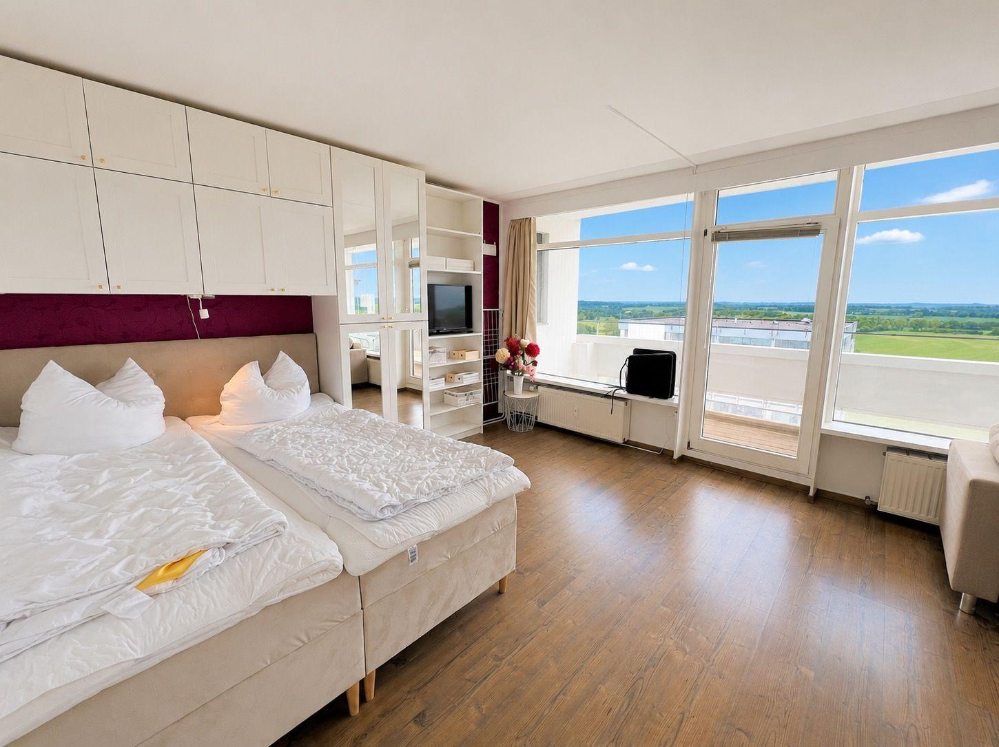 Room with double bed, built-in closet, and large window with view of the landscape.
