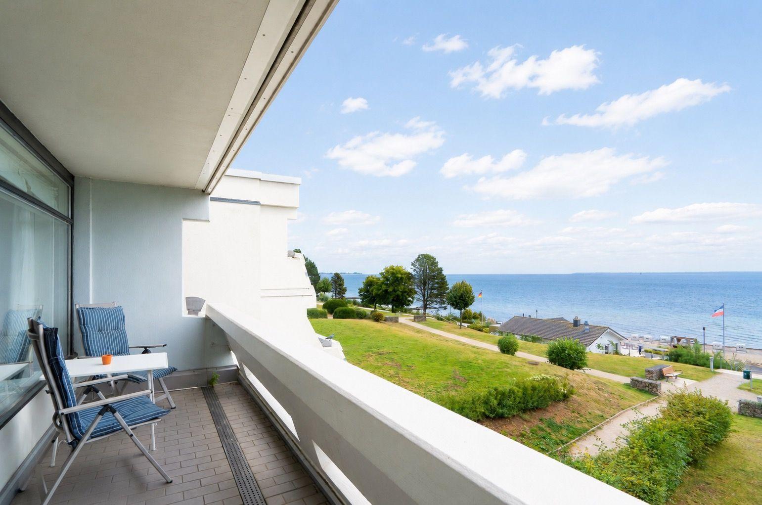 Terrasse mit Sitzgelegenheiten und Blick auf das Meer und Grünflächen.