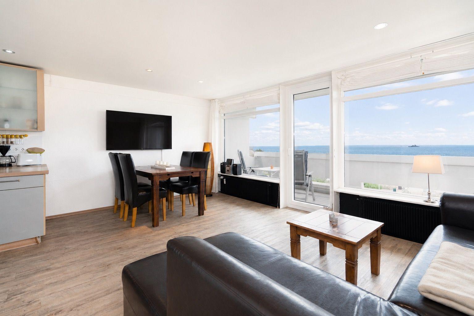 Wohnzimmer mit Küchenbereich, Esstisch und Blick aufs Meer.