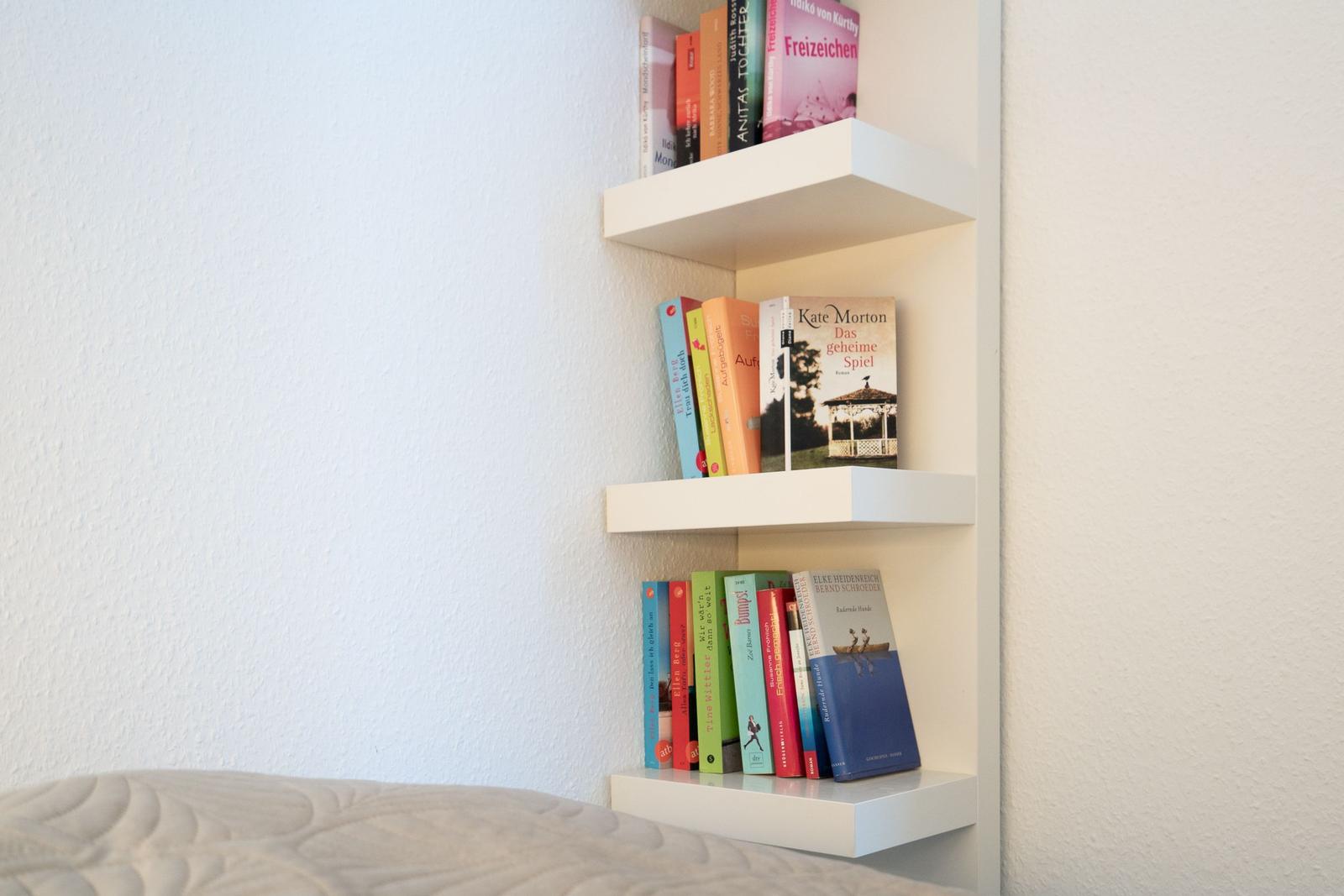 Wandregal mit drei Ebenen und Büchern im Schlafzimmer