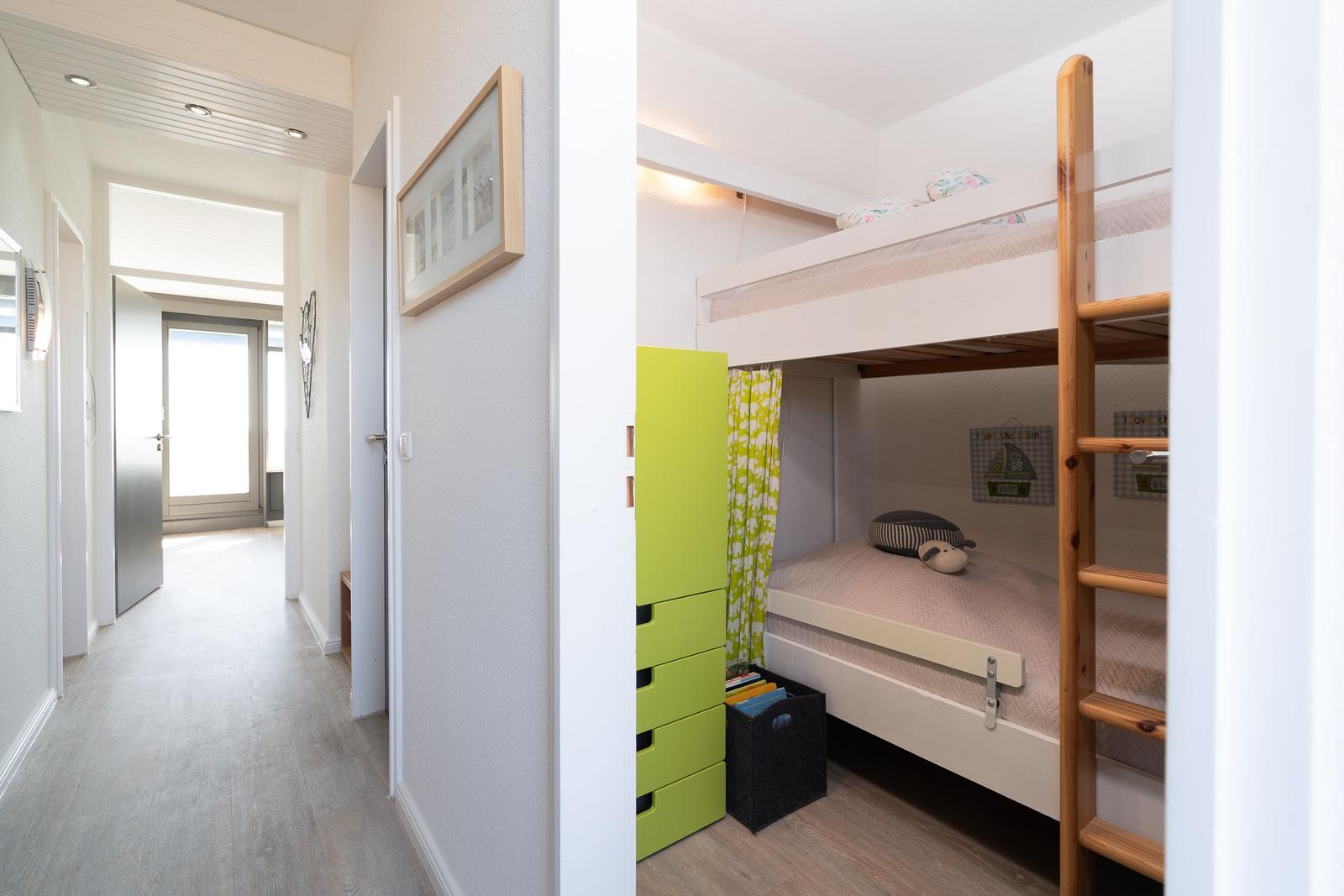Kinderzimmer mit Hochbett, grünem Schrank und Holzleiter.