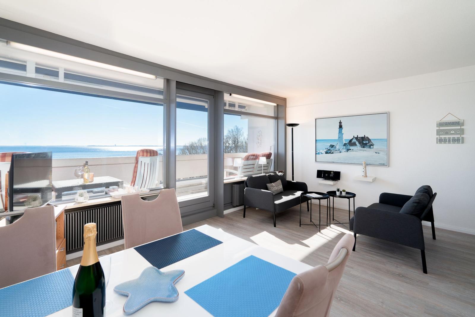 Wohn- und Essbereich mit Meerblick, Sofa, Stühle und Tisch mit Plastikdecken.