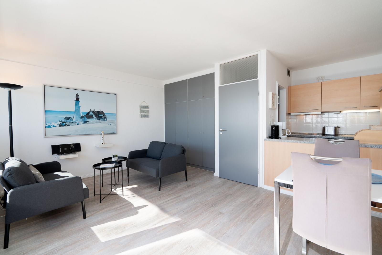 Wohnbereich mit Küchenzeile und Schlafzimmer. Wohnzimmer mit Sofa und Wandbild.