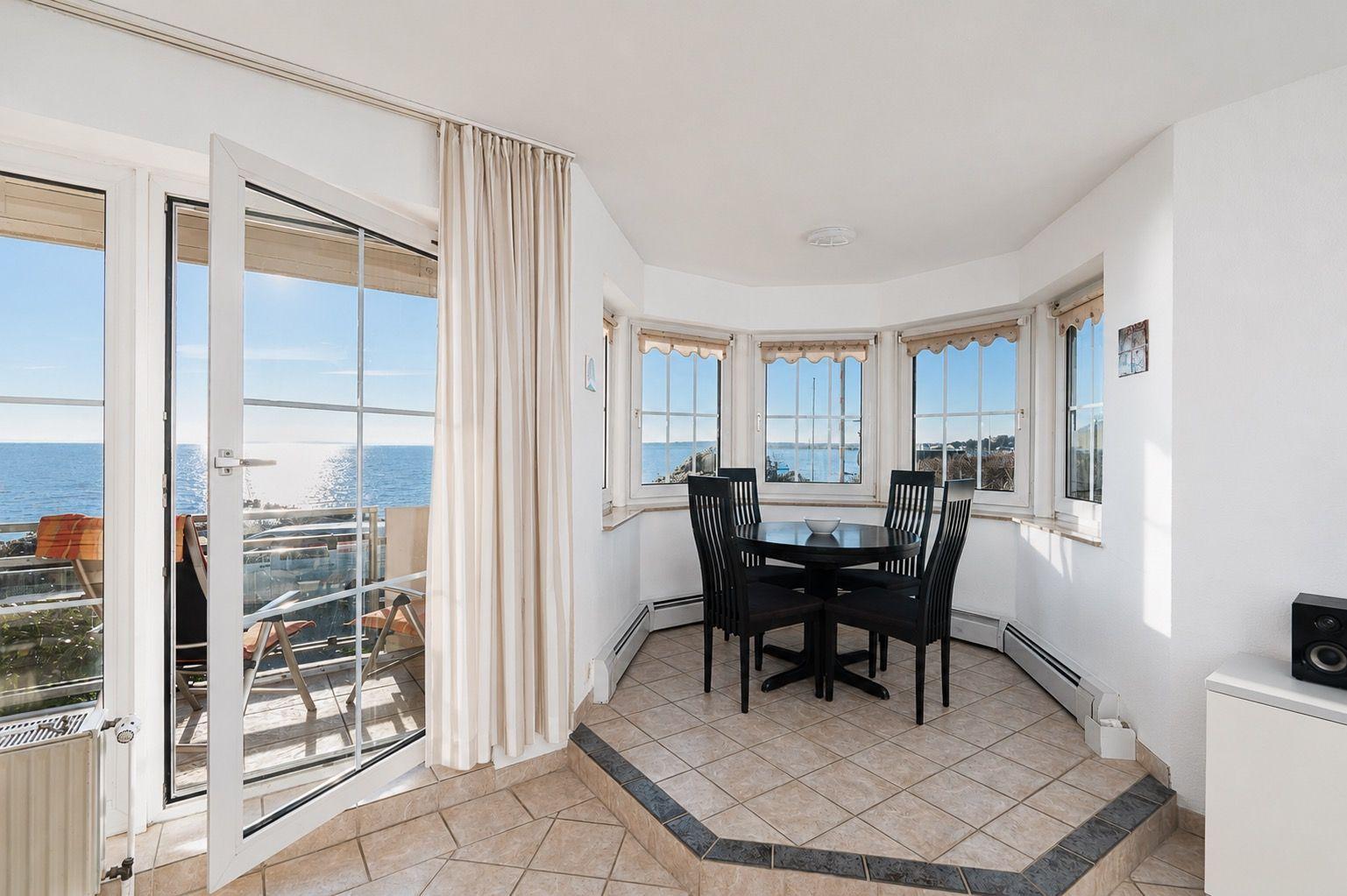 Dining room with sea view and balcony. Black table and chairs.