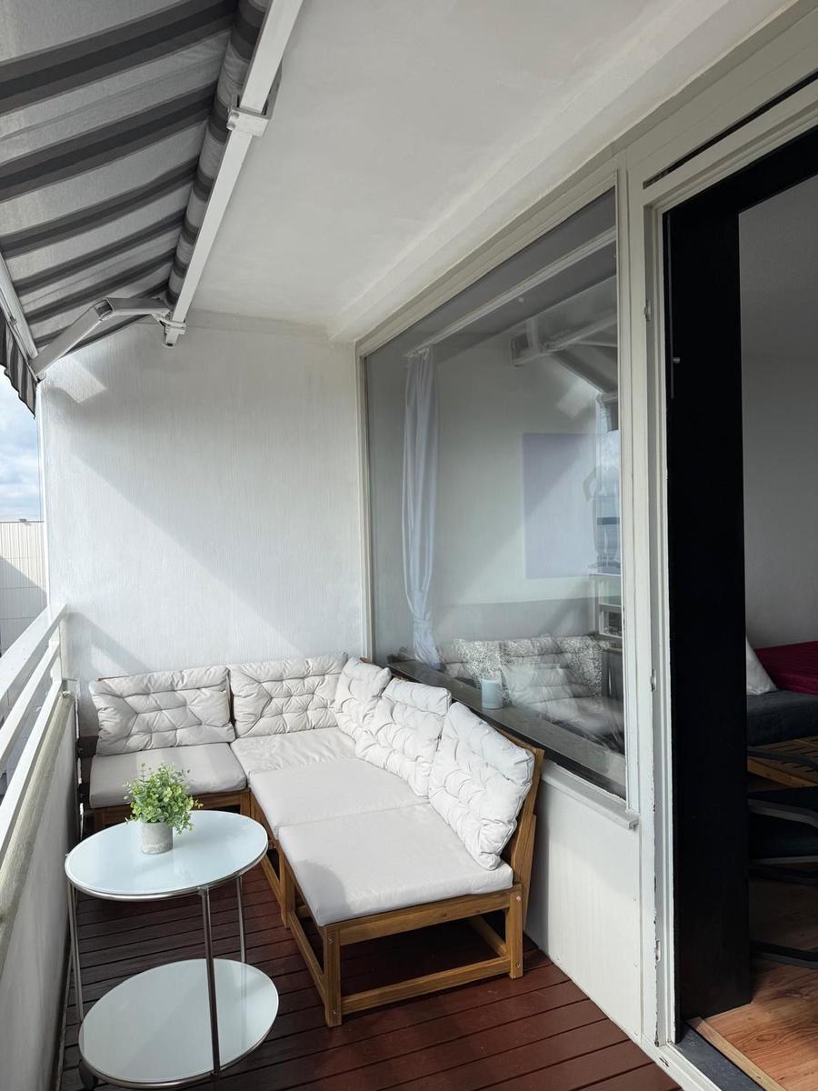 Terrasse mit Sitzgruppe, Tisch und Sonnenschutz. Durchgang ins Innere.