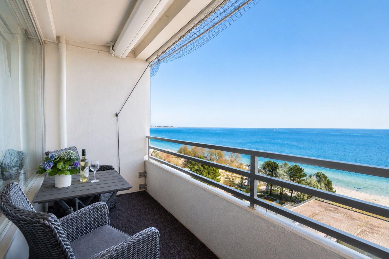 Balcony with table, chairs, and view of the sea.