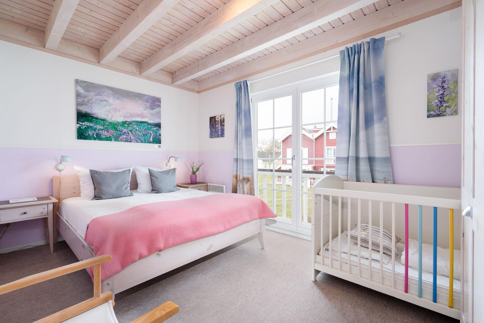 Schlafzimmer mit Bett, Kinderbett und Balkonansicht.