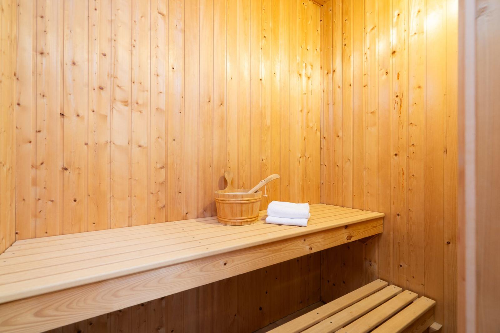 Sauna mit Holzbank, Eimer und Handtuch.