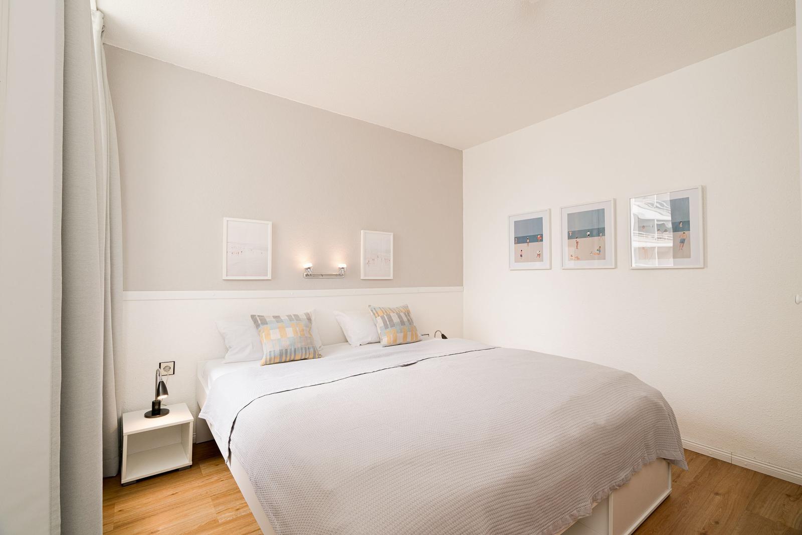 Schlafzimmer mit Bett, Nachttisch und Bildern an der Wand.
