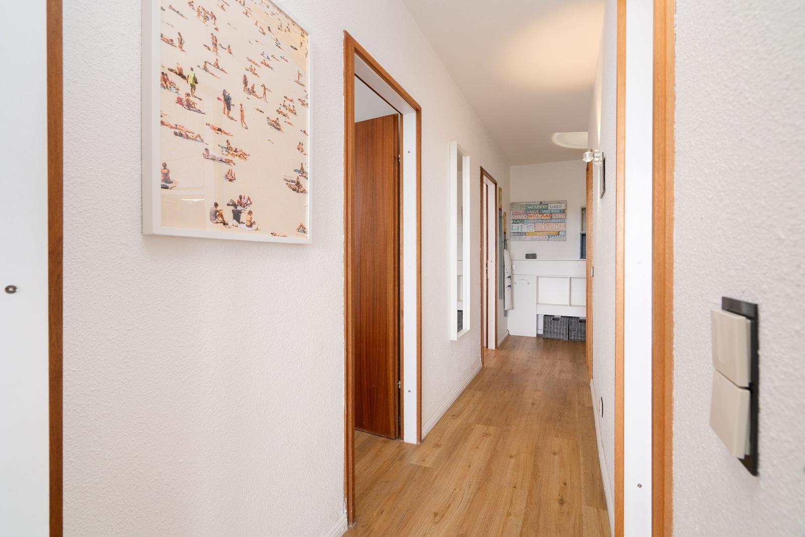 Flur mit Holzboden, Türen und Wandbildern