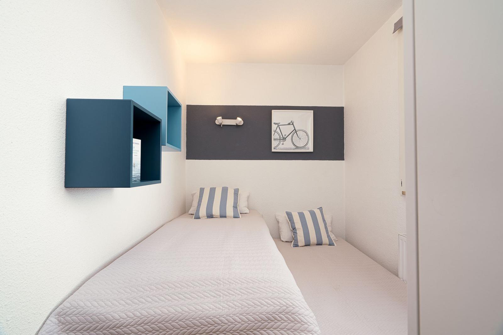 Schlafzimmer mit Bett, Kissen und Wandregal.