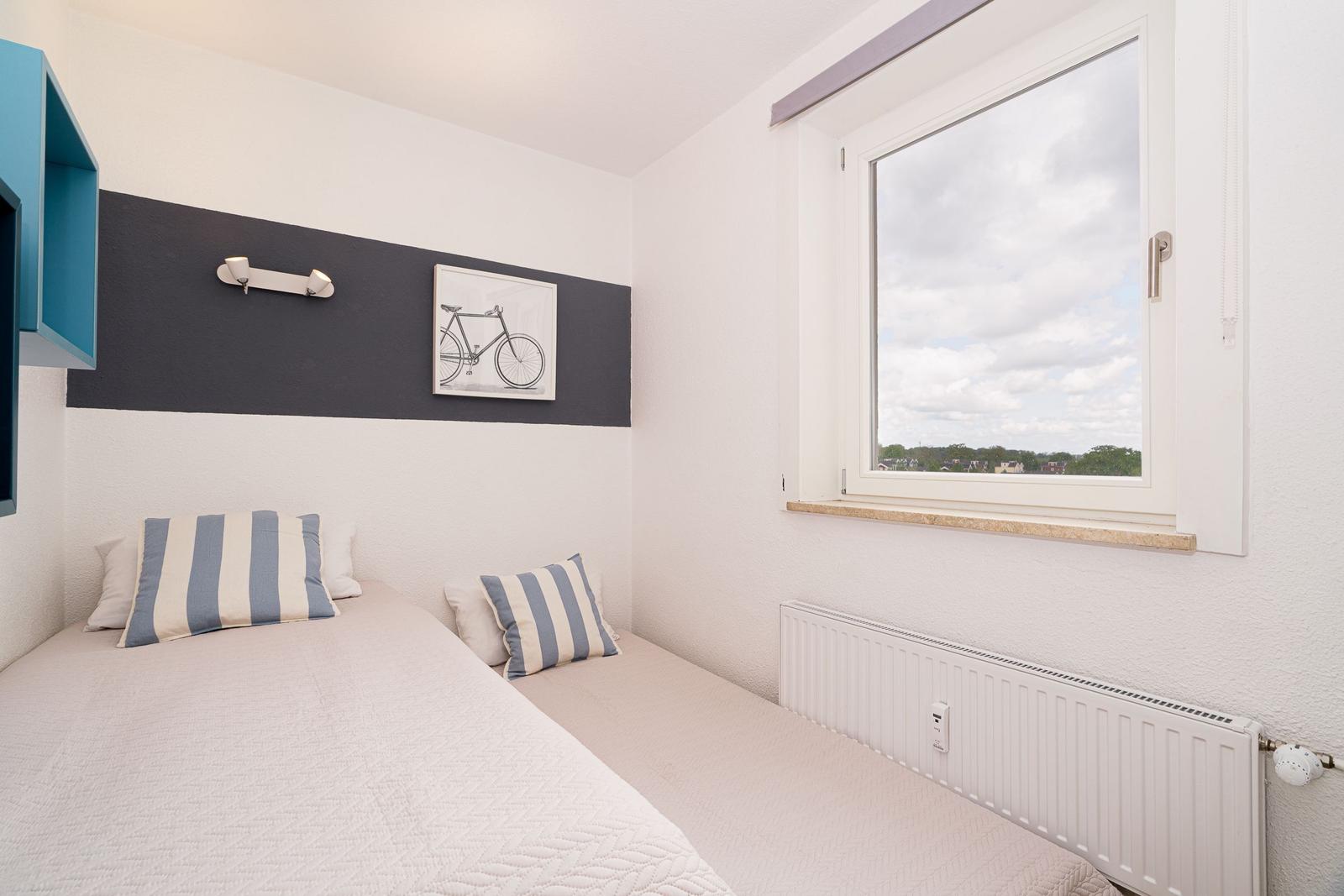 Schlafzimmer mit Bett, Fenster und Wandbild mit Fahrrad.