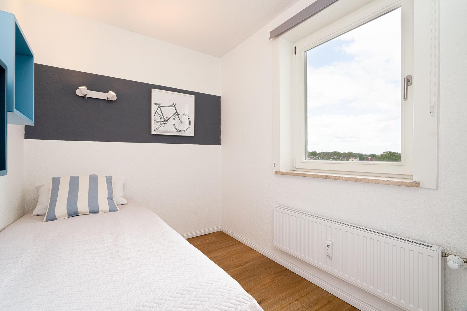 Schlafzimmer mit Bett, Fenster und Wanddekoration.