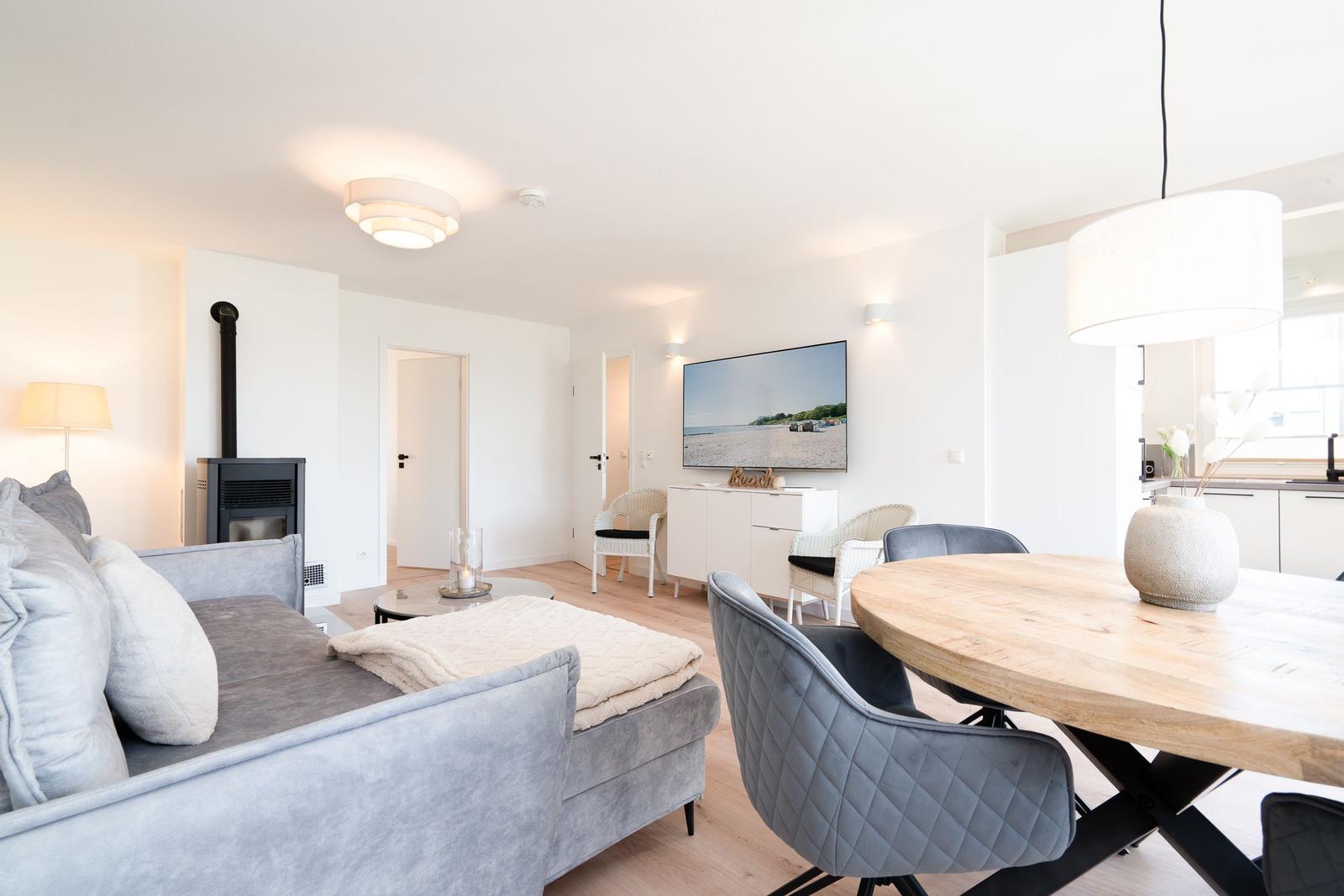 Wohn- und Essbereich mit Sofa, Esstisch und Fernseher an der Wand.