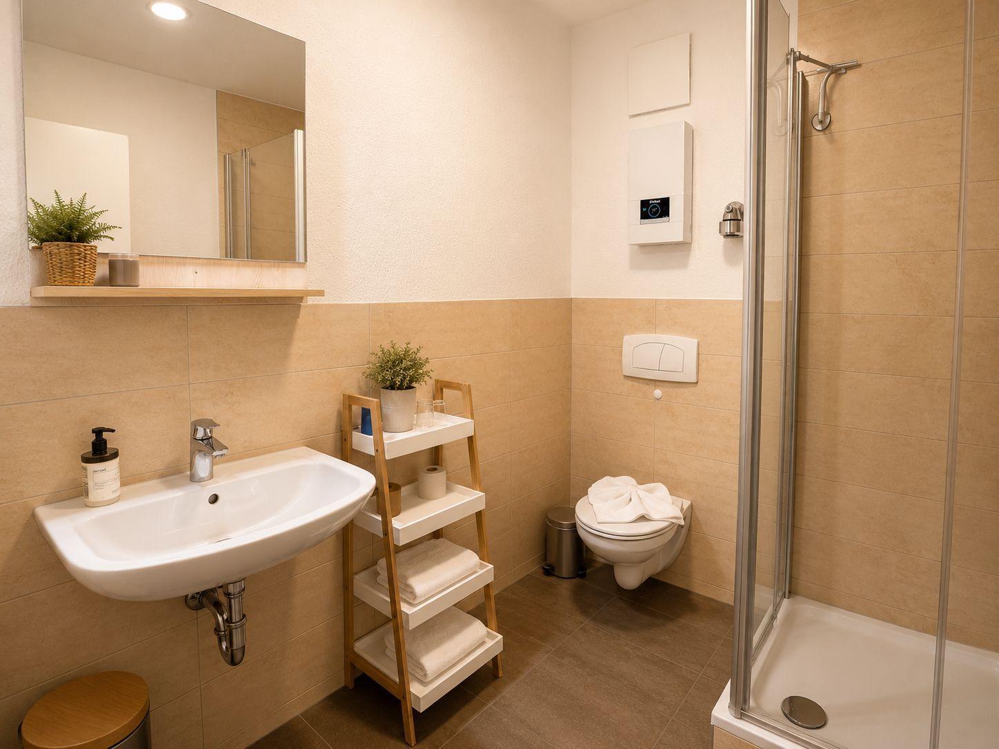 Badezimmer mit Dusche, Waschbecken, Toilette und Handtuchständer.