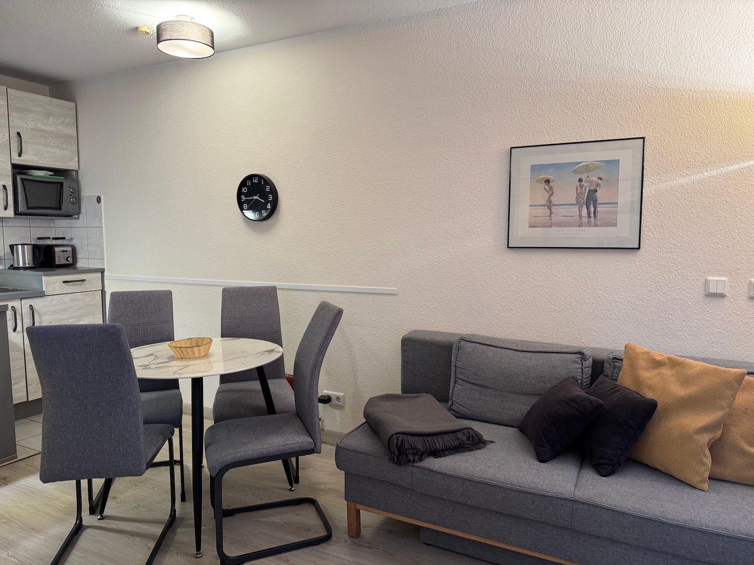 Living and dining area with sofa, table, and kitchenette.