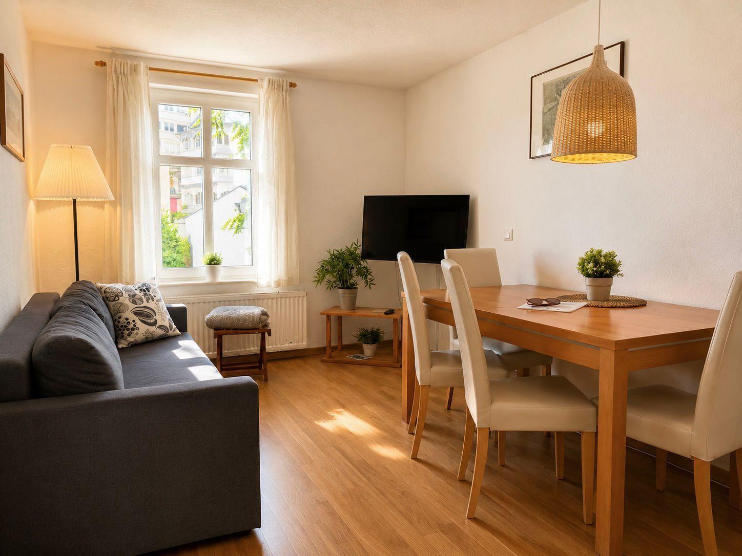 Wohn- und Essbereich mit Sofa, Esstisch und Fenster.