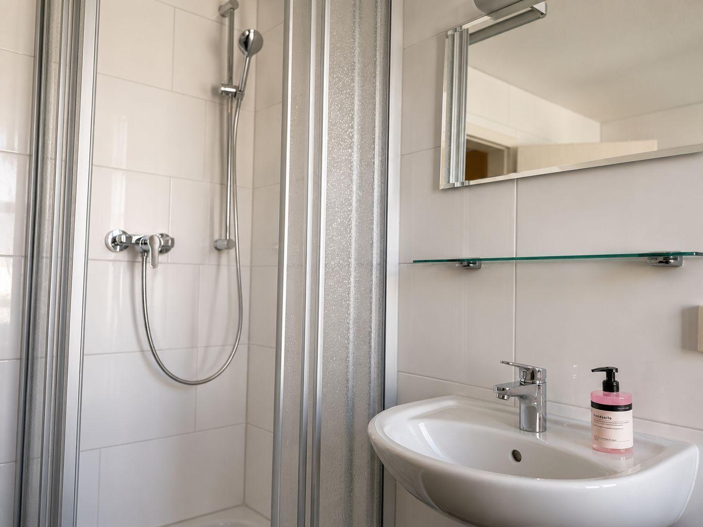 Bad mit Dusche, Waschbecken und Spiegel