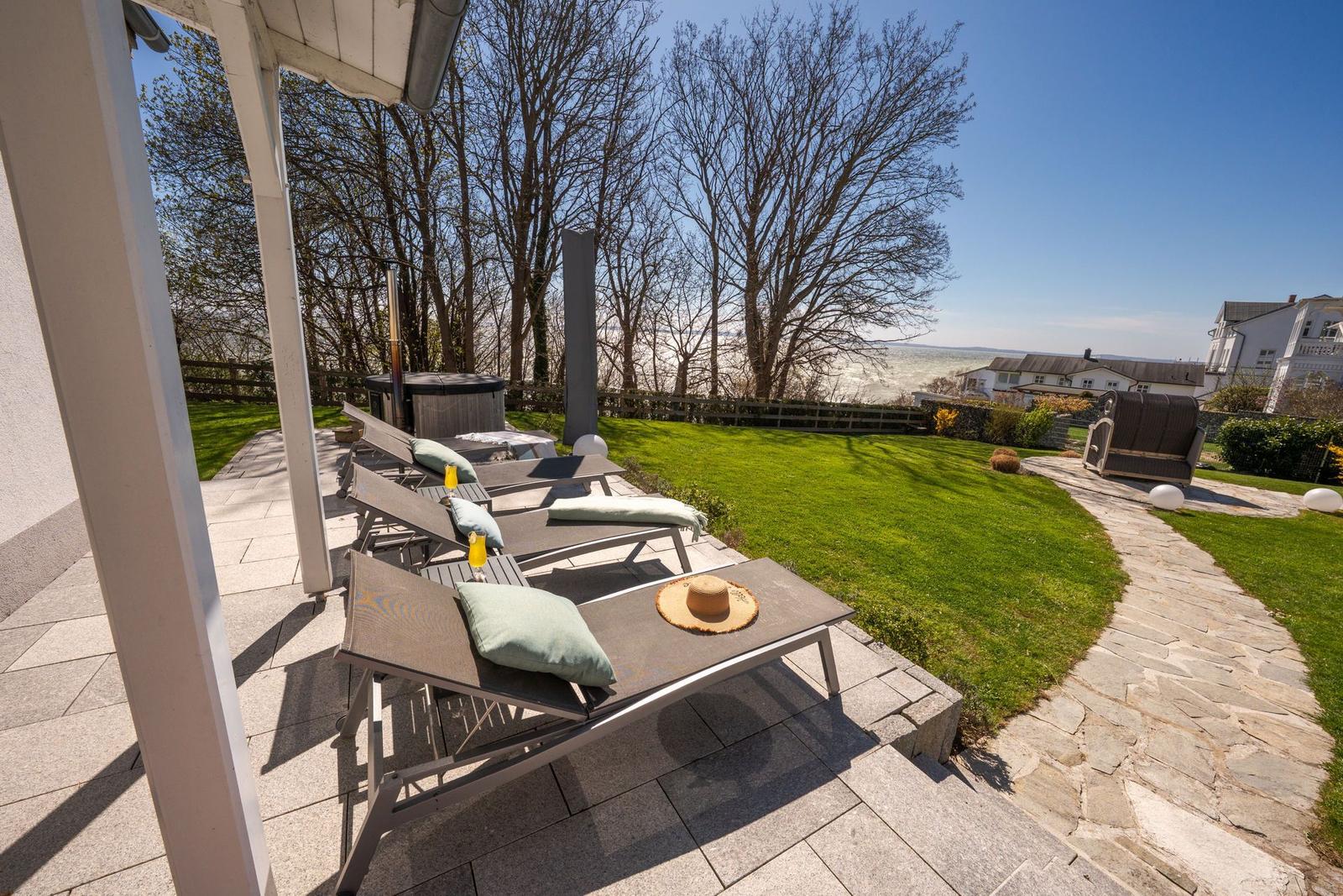 Terrasse mit Liegestühlen, Whirlpool und Blick auf den Garten und die Landschaft.