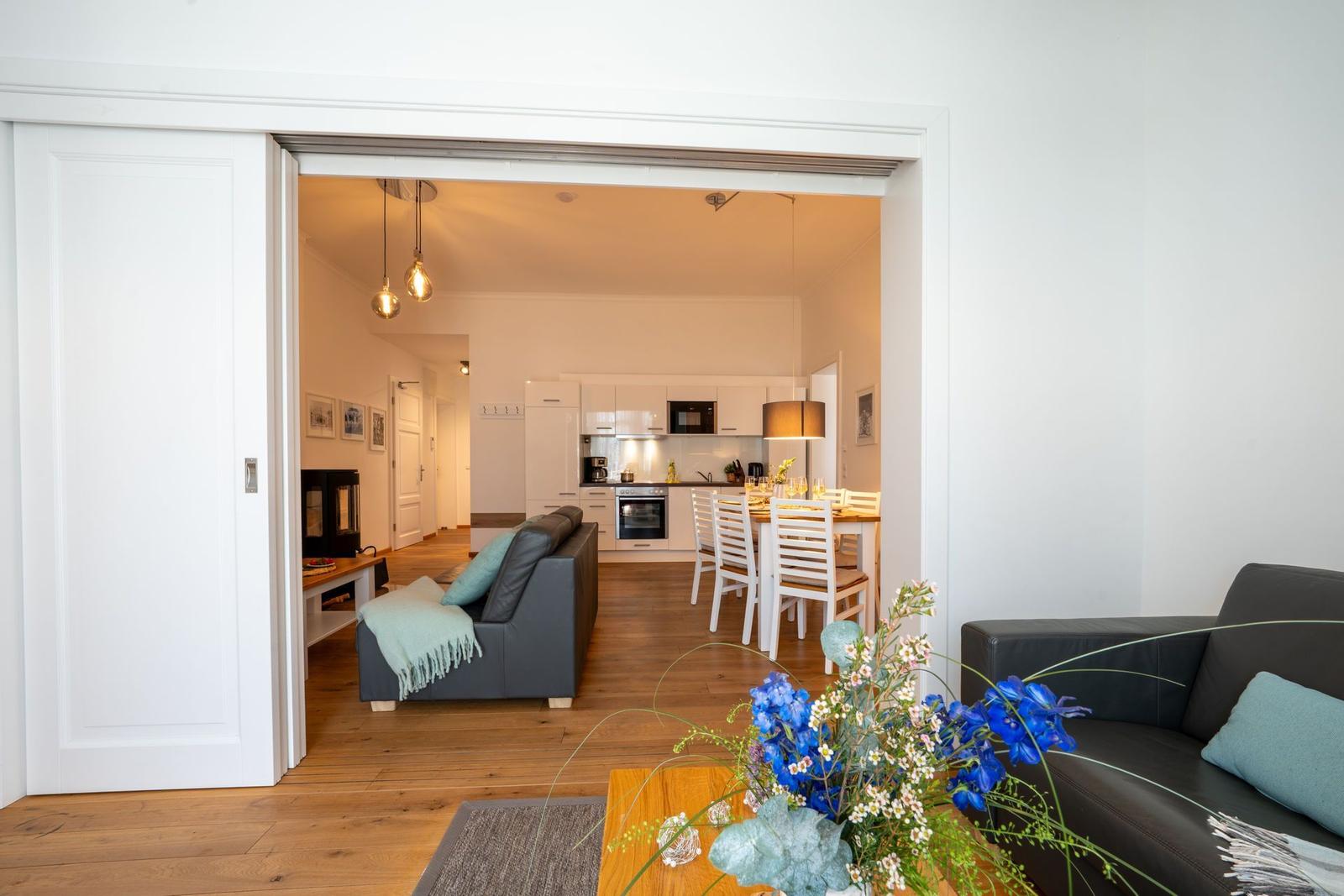 Wohnzimmer mit Sitzgelegenheit, Blick in Küche und Essbereich mit Tisch und Stühlen.