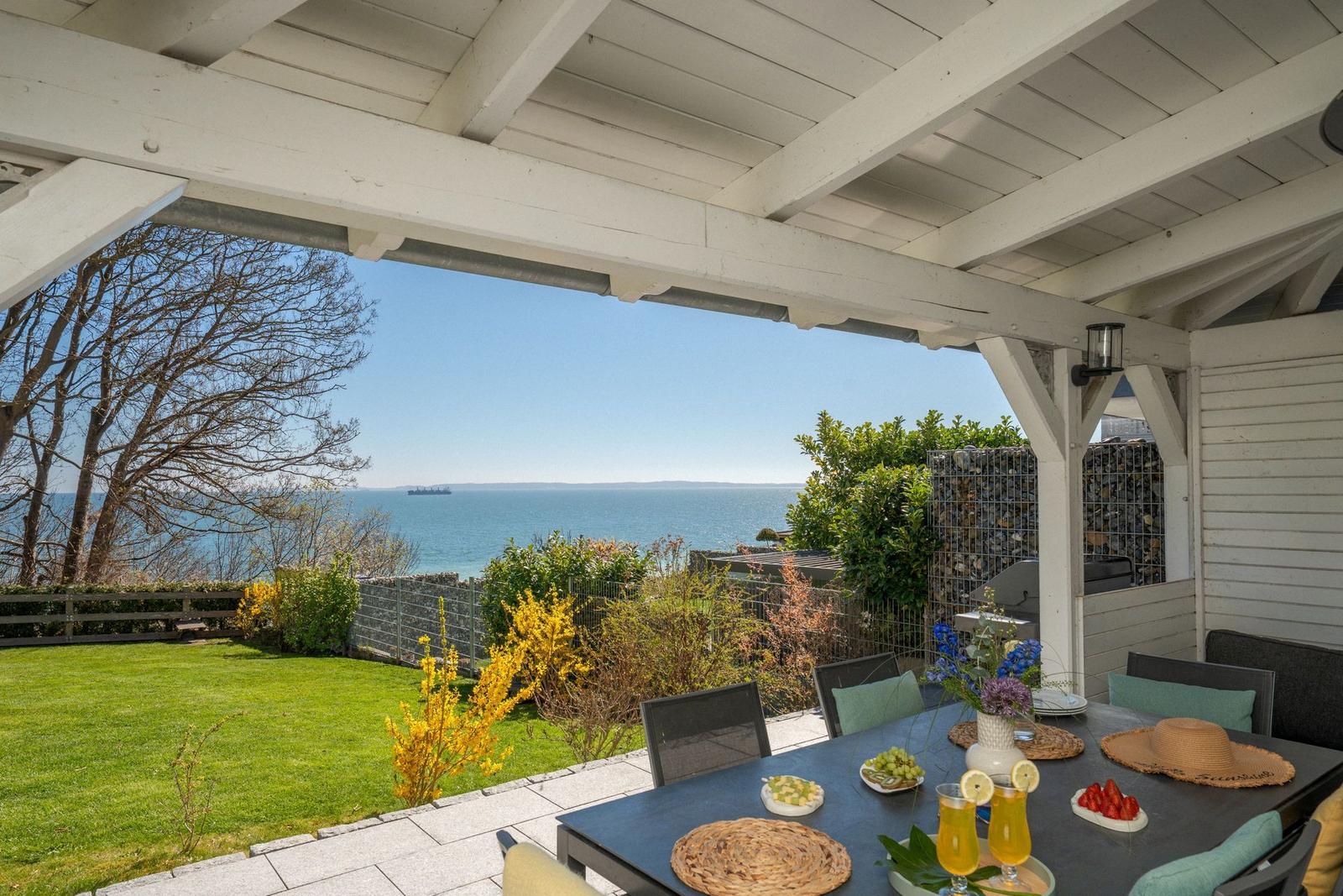 Terrasse mit Blick auf das Meer, gedeckter Tisch mit Obst und Getränken.