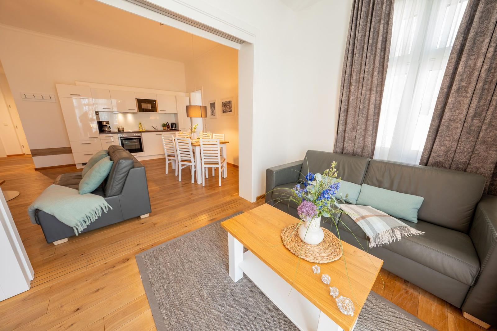 Wohnzimmer mit Sofa, Couchtisch und Blick in die Küche.