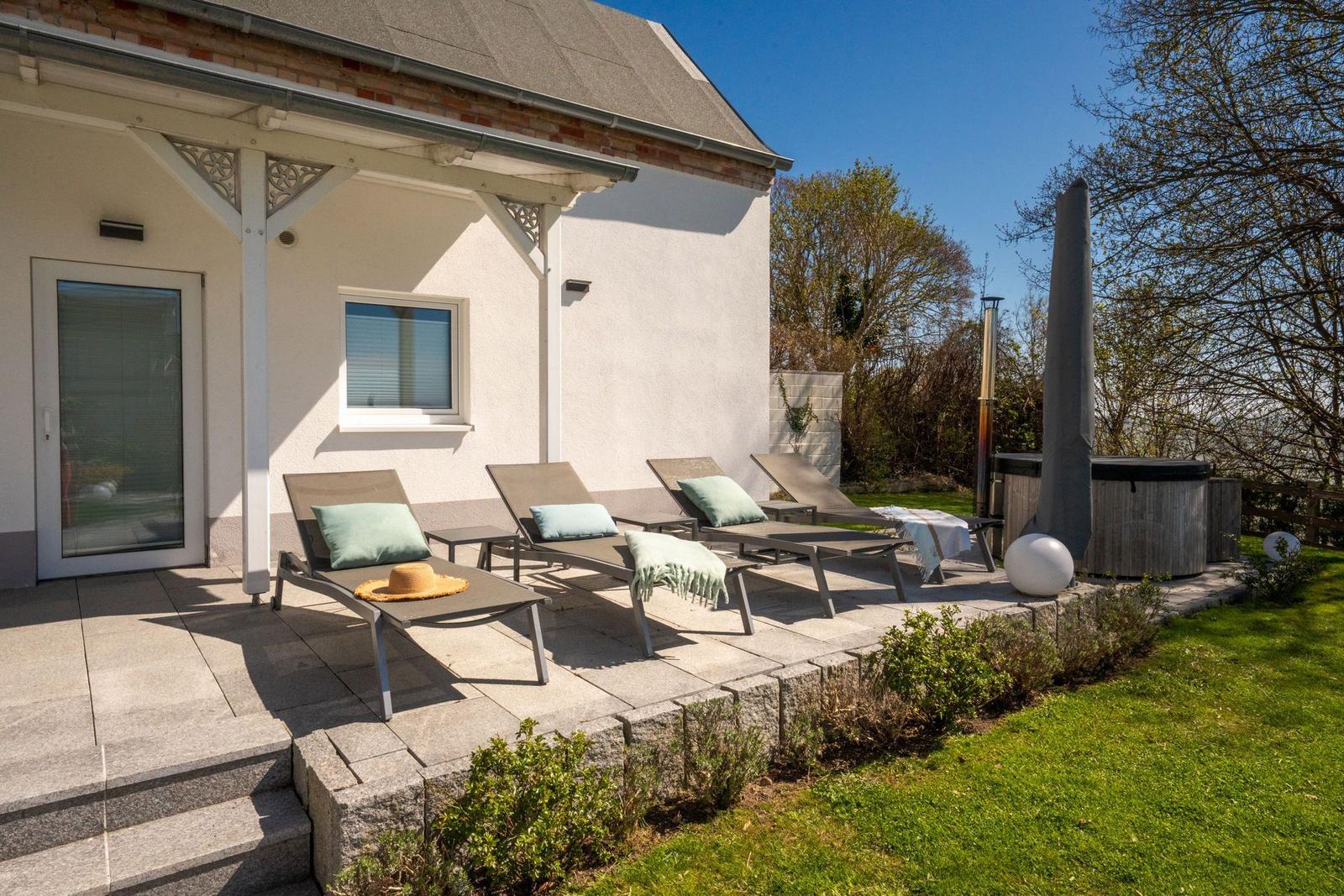Terrasse mit Liegestühlen, Whirlpool und Gartenbereich.