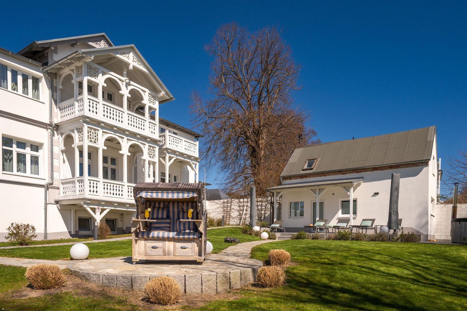 Haus mit Balkon, Strandkorb und Garten. Sonniger Tag mit blauem Himmel.