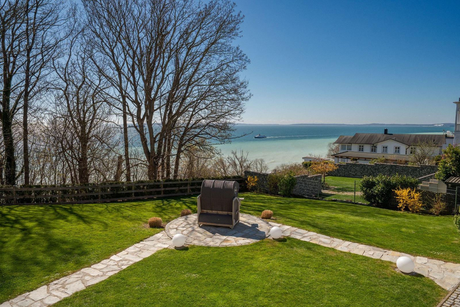 Garten mit Liegestuhl und Blick auf See und Haus.