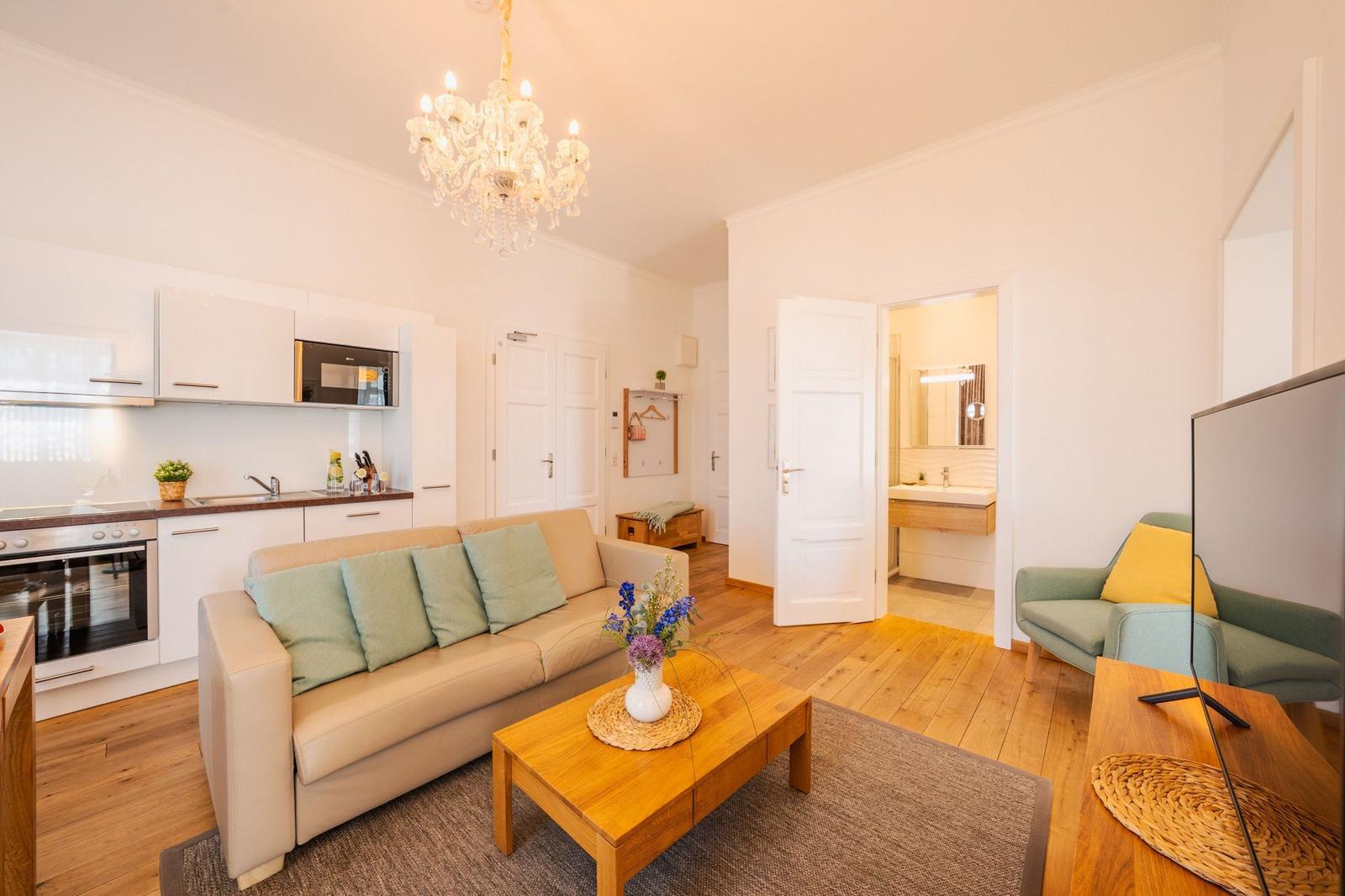 Wohnzimmer mit Sofa, Küchenbereich und Blick in das Bad.
