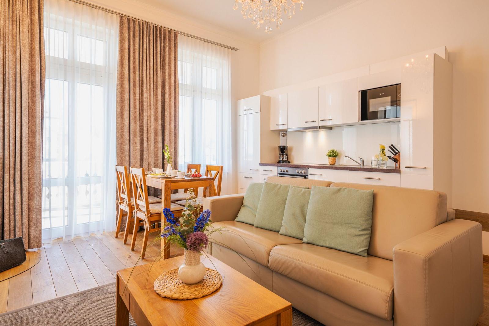 Wohn- und Essbereich mit Sofa, Tisch, Küchenzeile und Fenster